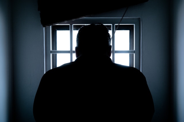 A man looks out of a window in his jail cell.